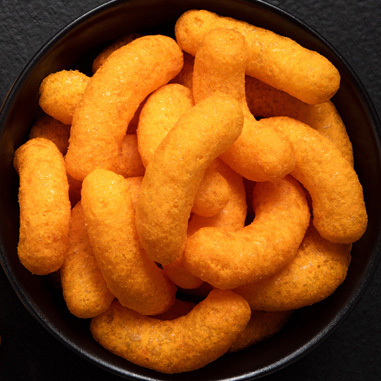 Puffed cheese snacks in a black bowl showing the snack texturizer application