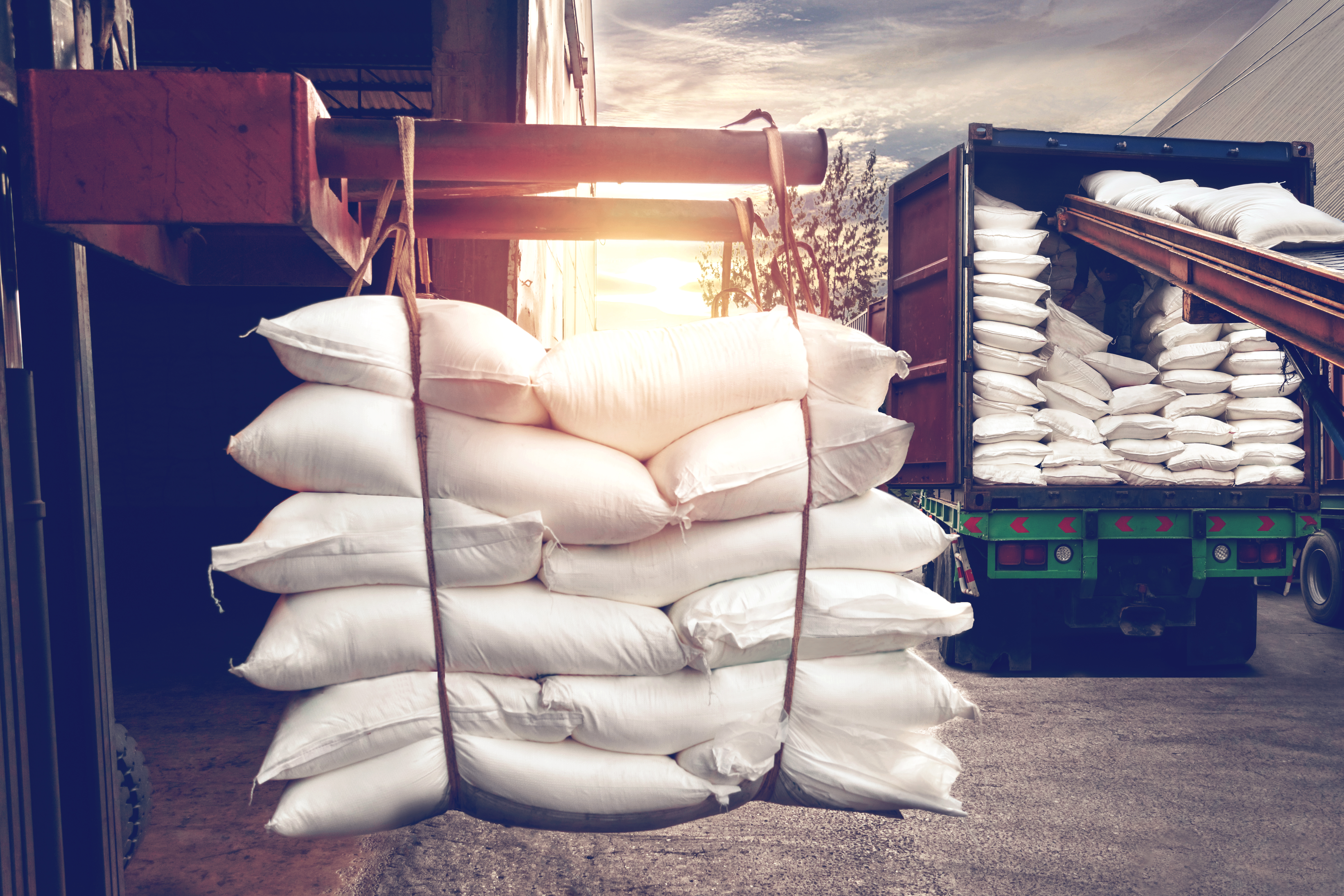 Forklift handling white sugar bags from warehouse for stuffing into container truck for export, vintage tone.